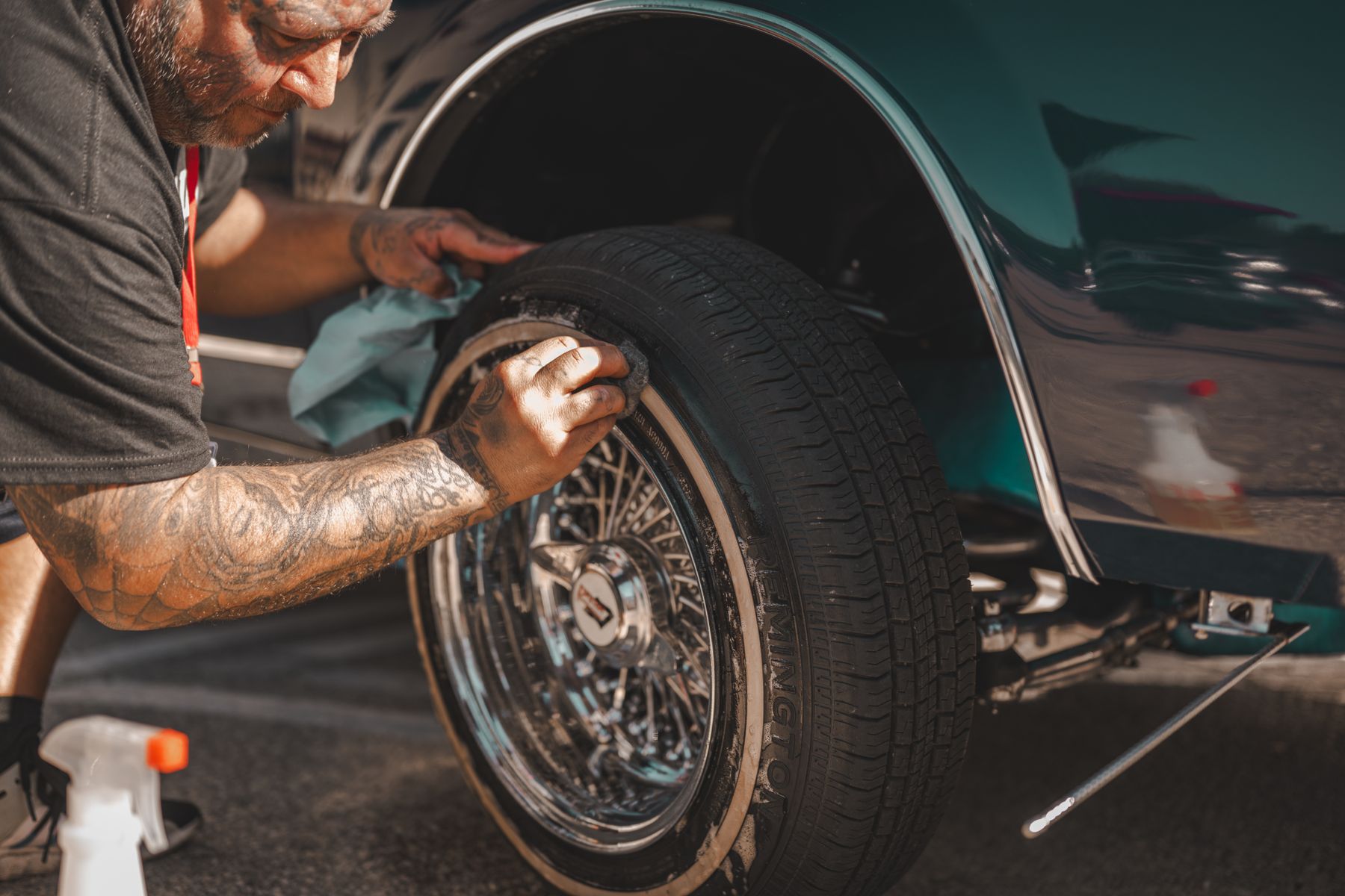 A technician wiping and detailing a classic vehicle wheel